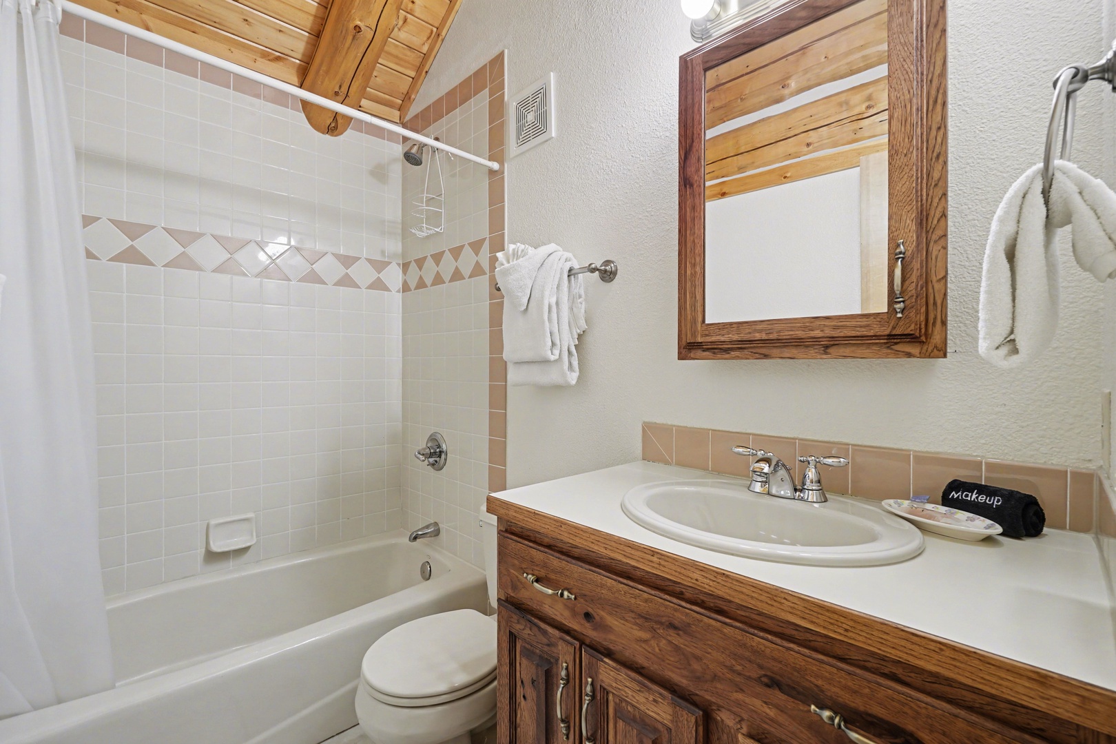 Refresh in your private bathroom featuring warm wood accents, tiled tub-shower combo, and thoughtful amenities for your comfort.