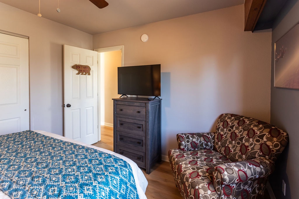 Relax in your cozy bedroom with exposed wooden beams, comfortable seating, and modern entertainment at your fingertips.