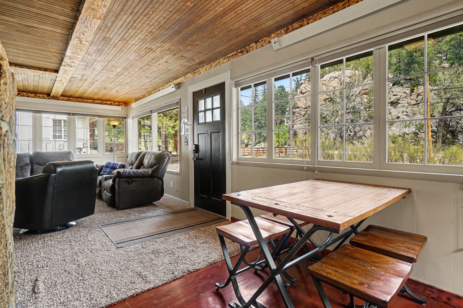 Step into your sunlit retreat where rustic charm meets mountain serenity. Floor-to-ceiling windows frame stunning rock formations, inviting natural light to dance across cozy recliners and warm wood accents.