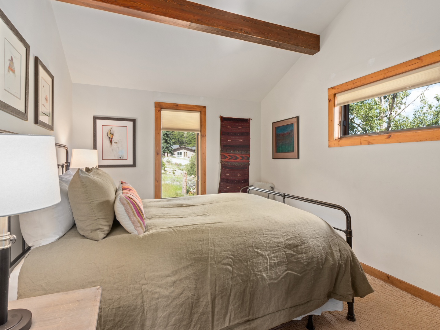 Drift off in your cozy bedroom featuring rustic beams overhead, natural light, and thoughtful artwork creating a peaceful retreat.