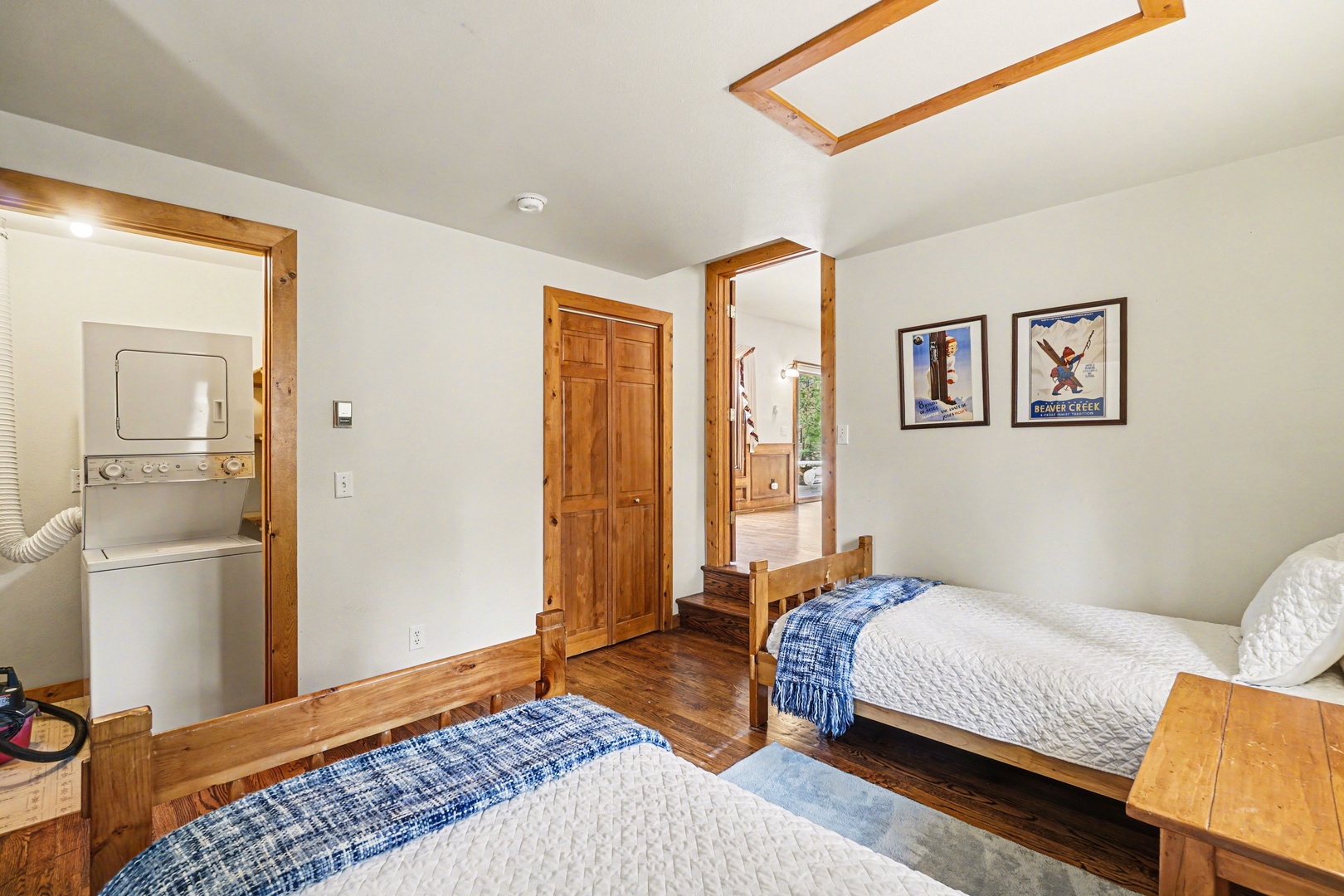 Your mountain retreat bedroom features twin beds with cozy blue throws, warm wood accents, and convenient in-room laundry—perfect for restful nights.