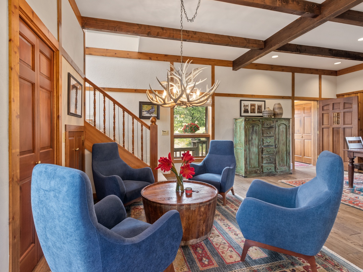 Sink into plush blue chairs beneath antler chandeliers where rustic beams frame your mountain retreat conversations.
