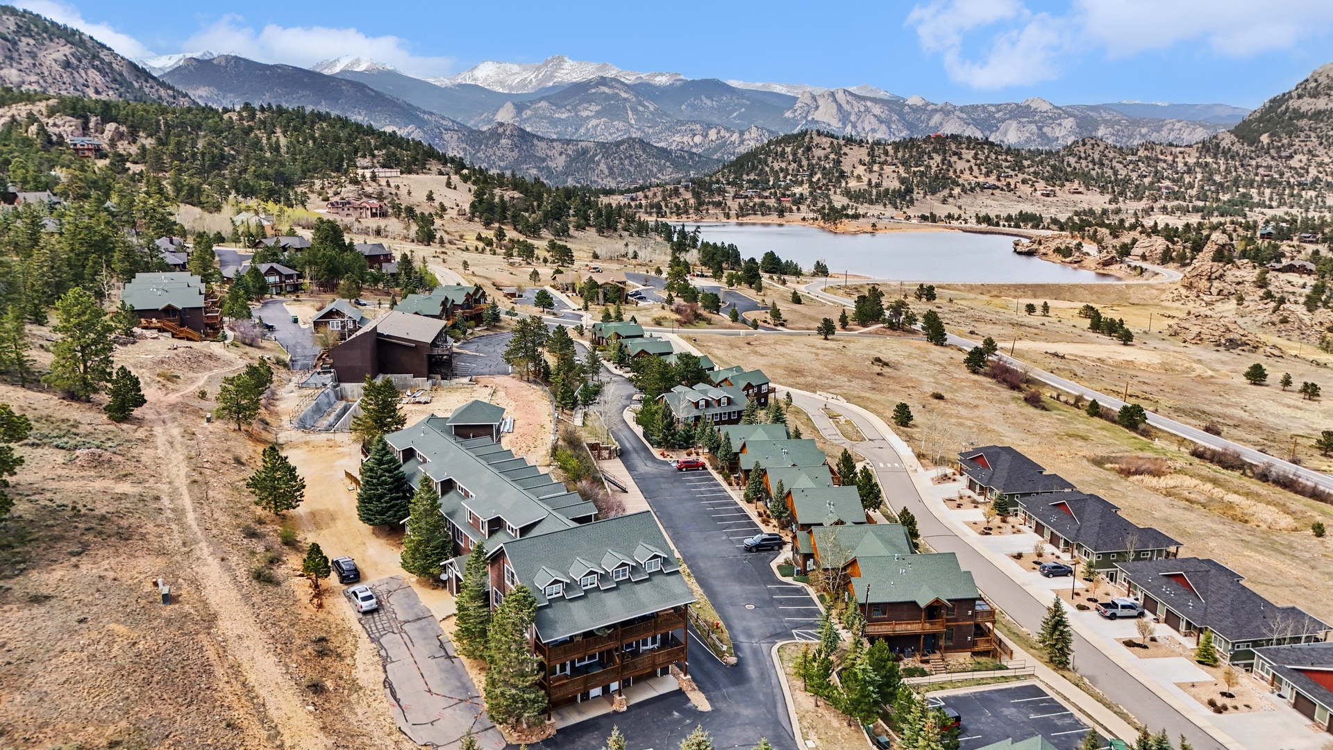 Mountain resort community nestled in scenic valley with lake views and dramatic peak backdrop.