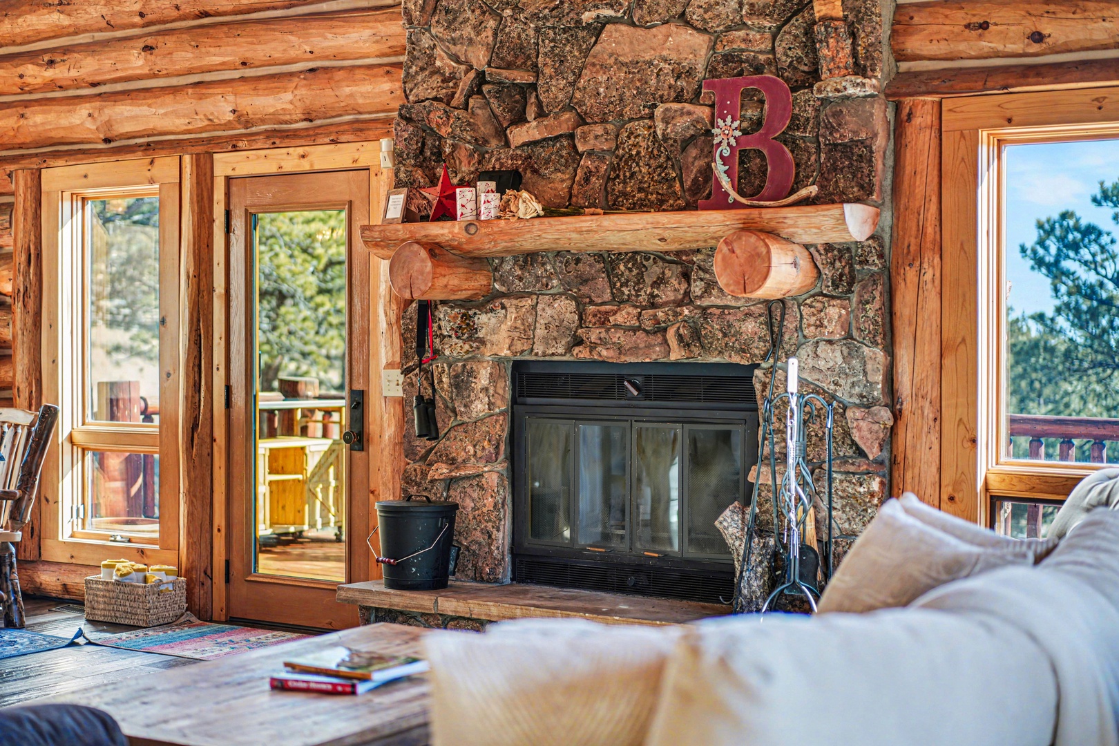 Cozy up by your stone fireplace with rustic charm, where warm wood beams and soft seating create the perfect mountain retreat atmosphere.