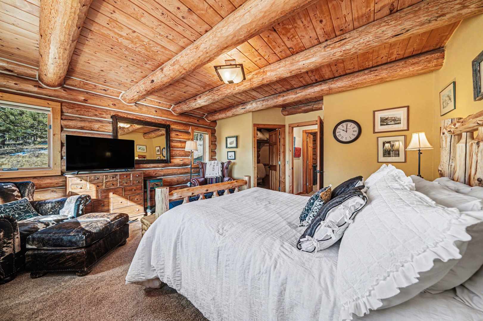 Unwind in this rustic log cabin bedroom where exposed beams meet crisp linens and mountain views beckon from your window.