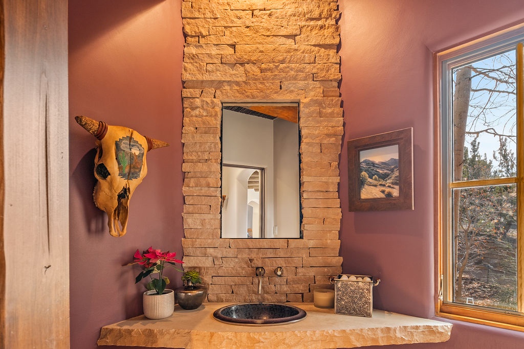 Unwind in this artistic restroom featuring natural stone accents, distinctive decor, and peaceful desert views through your window.