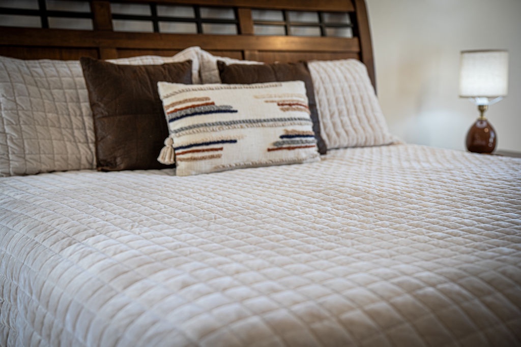Sink into plush quilted bedding with artisan striped pillows. Your cozy retreat awaits with warm lighting and rustic wood accents.