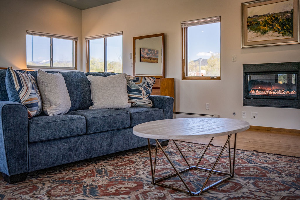 Sink into plush sofas by your crackling fireplace, enjoying mountain views through expansive windows in this bright, comfortable living space.