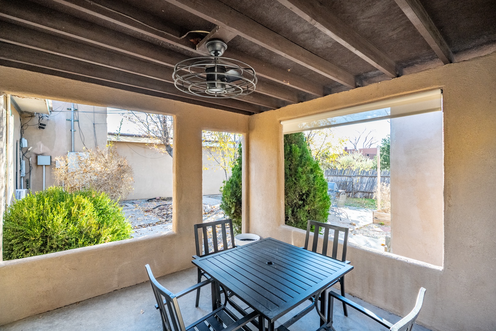 Your covered outdoor dining space features exposed beam ceilings and a modern ceiling fan, perfect for enjoying meals al fresco while overlooking the landscaped backyard.