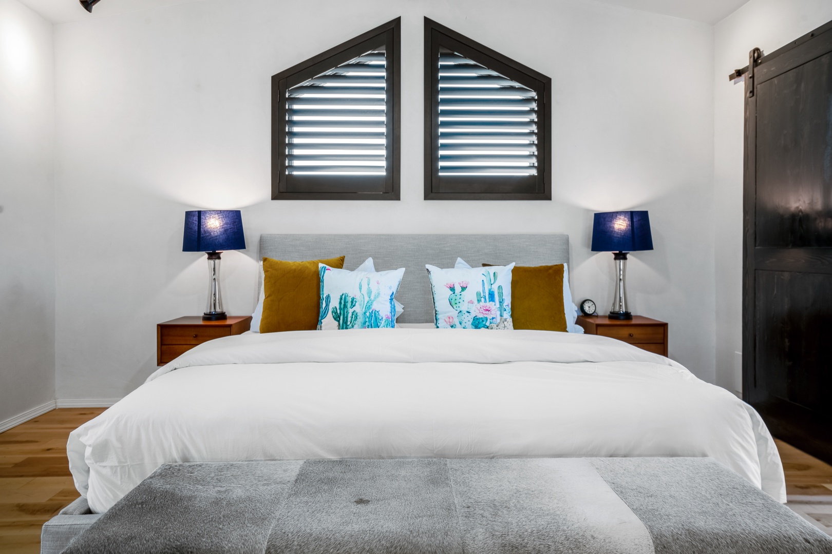 Sink into this plush bed with crisp linens and colorful accent pillows. Your peaceful retreat features elegant bedside lamps and stylish shuttered windows.