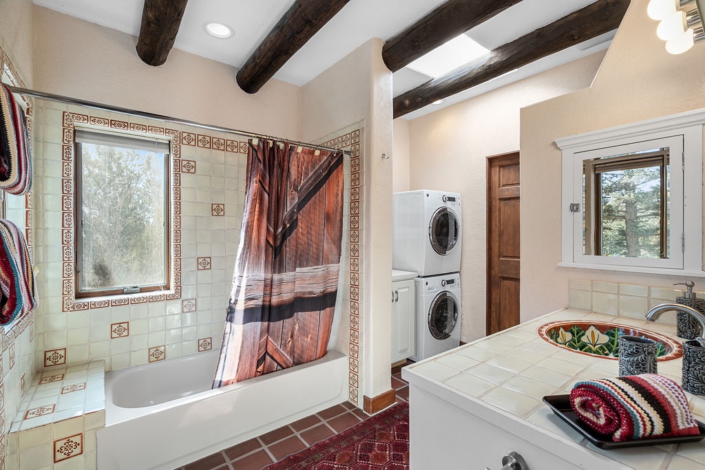 Step into your spacious bathroom with rustic beams, decorative tiles, and convenient laundry facilities right at hand.