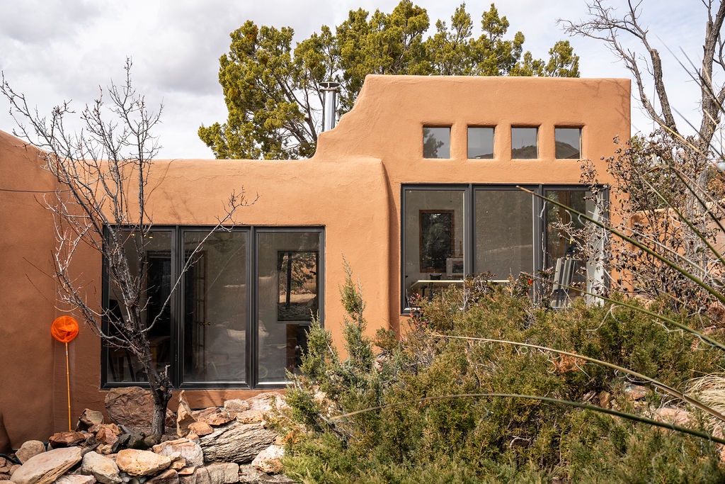 Modern adobe-style building nestled among native vegetation and natural landscaping in a desert setting.