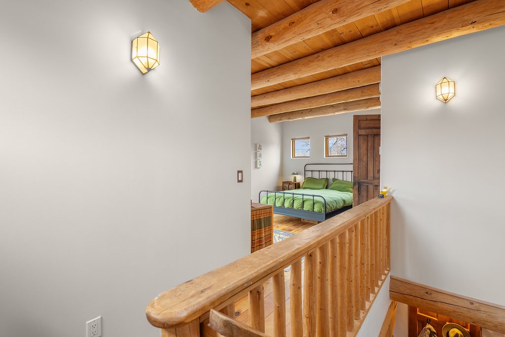 Rest peacefully in your cozy bedroom with rustic wooden beams overhead and warm lighting creating the perfect mountain retreat ambiance.