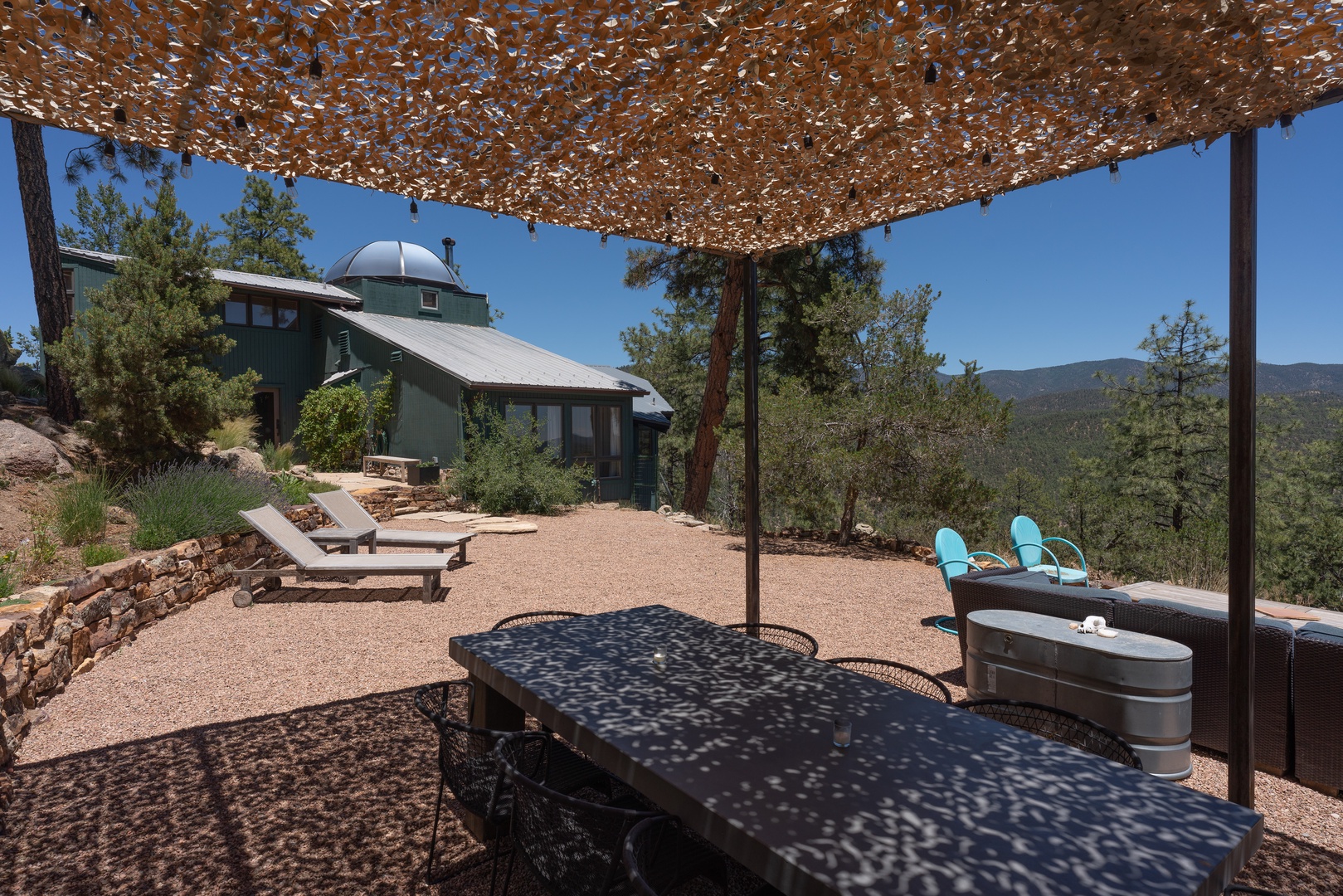 Shaded, peaceful seating under a camouflage canopy, nestled among pine and oak trees in natural surroundings.
