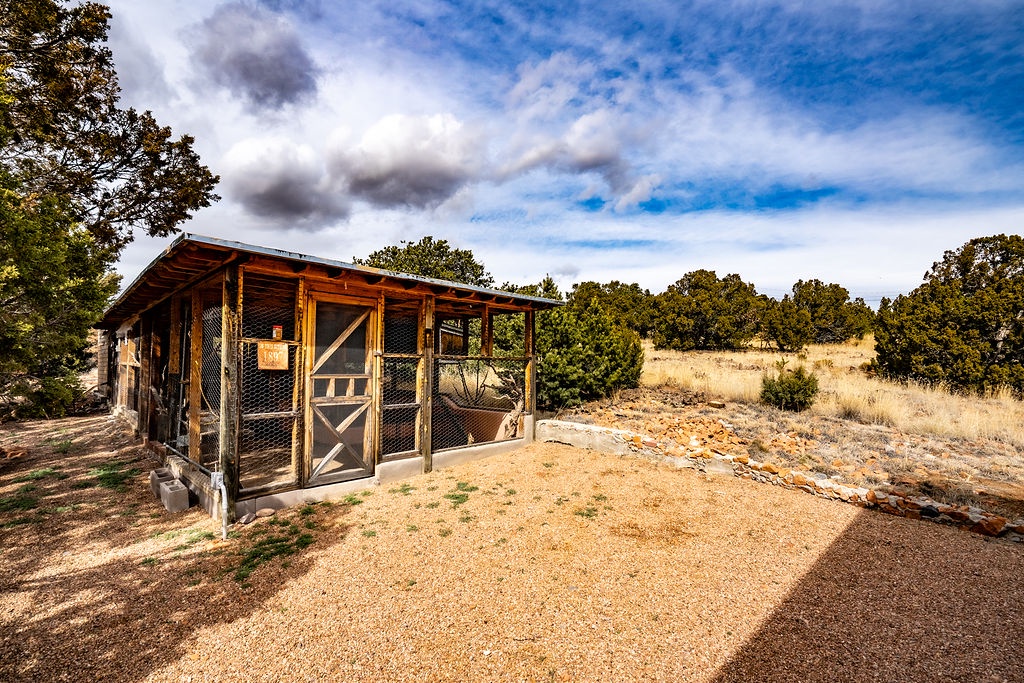 Rustic cabin nestled in rolling hills with golden grasslands and scattered oak trees under dramatic cloudy skies.