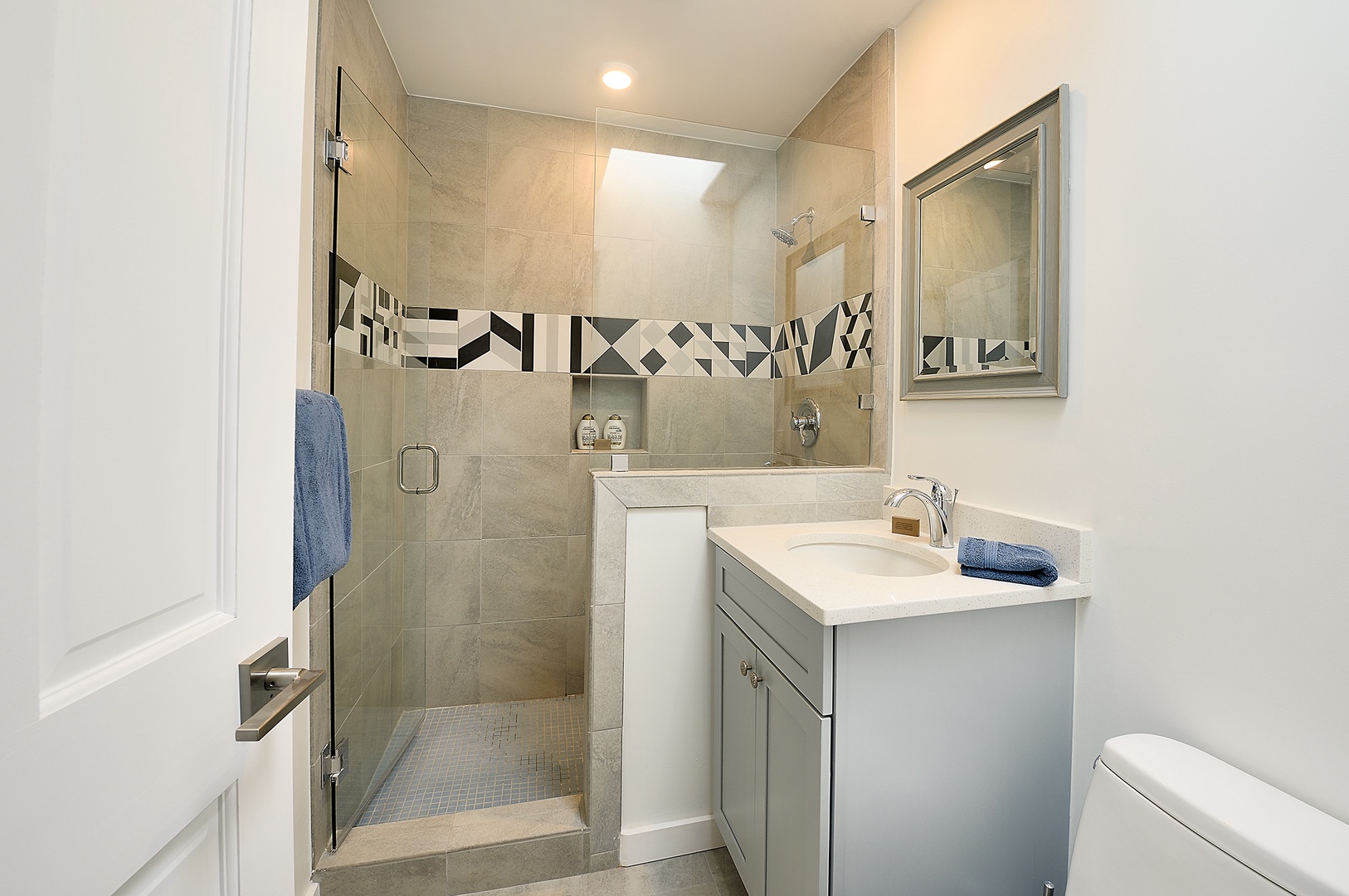 Step into your private bathroom featuring modern tile work, spacious walk-in shower, and thoughtful touches like soft towels waiting for you.