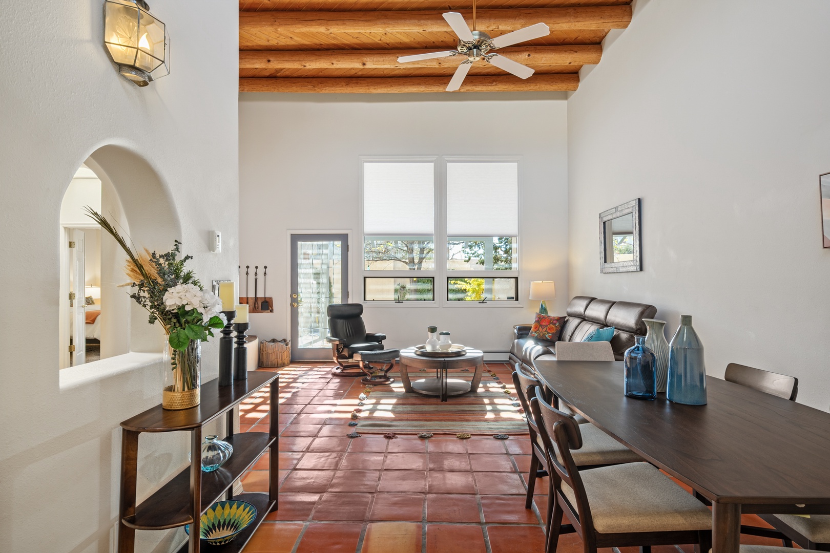 Relax in your stylish living space featuring exposed beam ceilings, comfortable leather seating, and abundant natural light streaming through large windows.