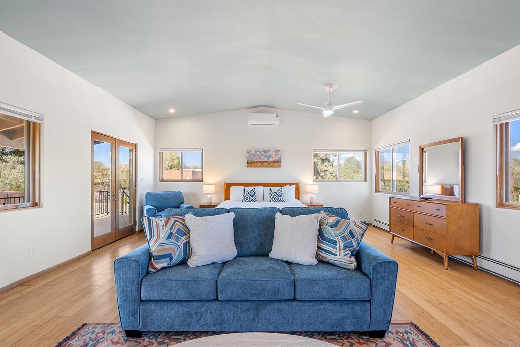 Relax in this bright, spacious bedroom with a cozy blue sofa for lounging and stunning natural views through every window.
