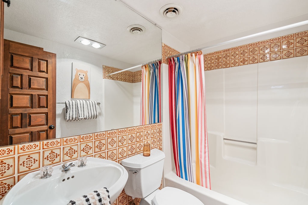 Your colorful bathroom features cheerful striped curtains and charming decorative tiles for a bright, welcoming start to each day.