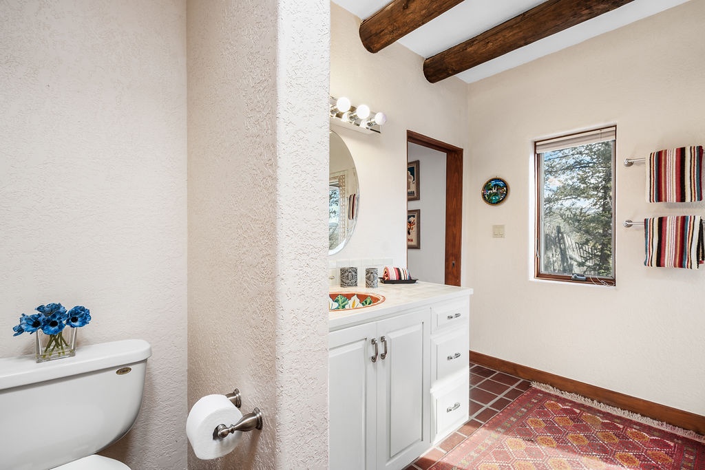 Refresh in your stylish bathroom with exposed wooden beams, vibrant local artwork, and peaceful garden views from the window.