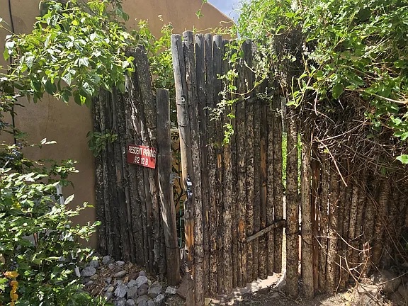 A rustic wooden gate welcomes you into a secluded outdoor area framed by leafy trees and natural sunlight, perfect for your private retreat.