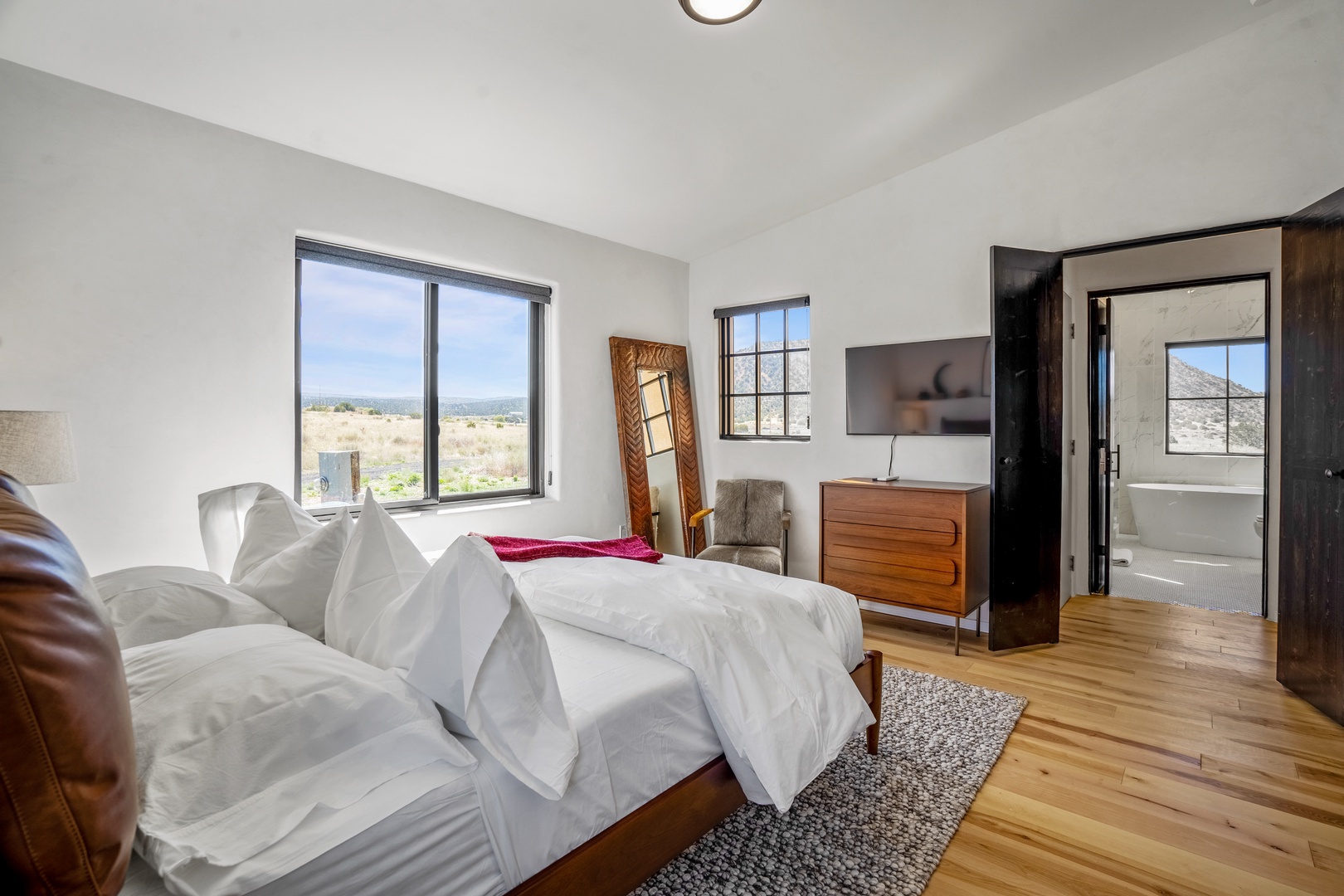Wake up to stunning views through expansive windows in your bright bedroom with warm hardwood floors and elegant modern furnishings.