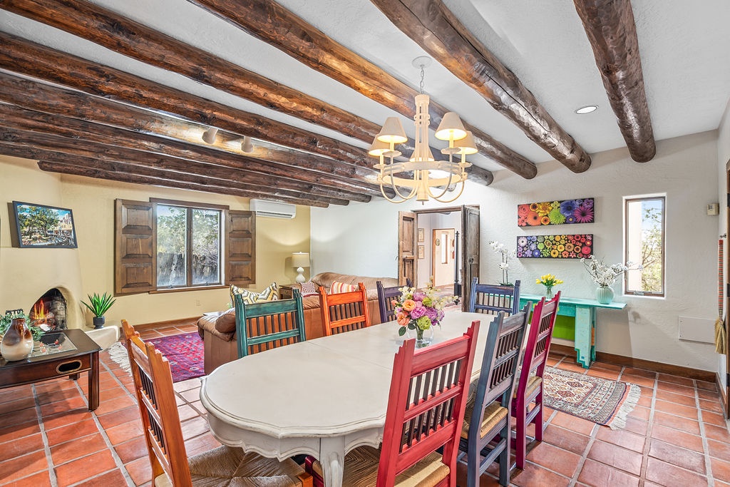 Gather around your colorful dining table under rustic beams, where every meal feels like a celebration in this warmly lit adobe-style space.