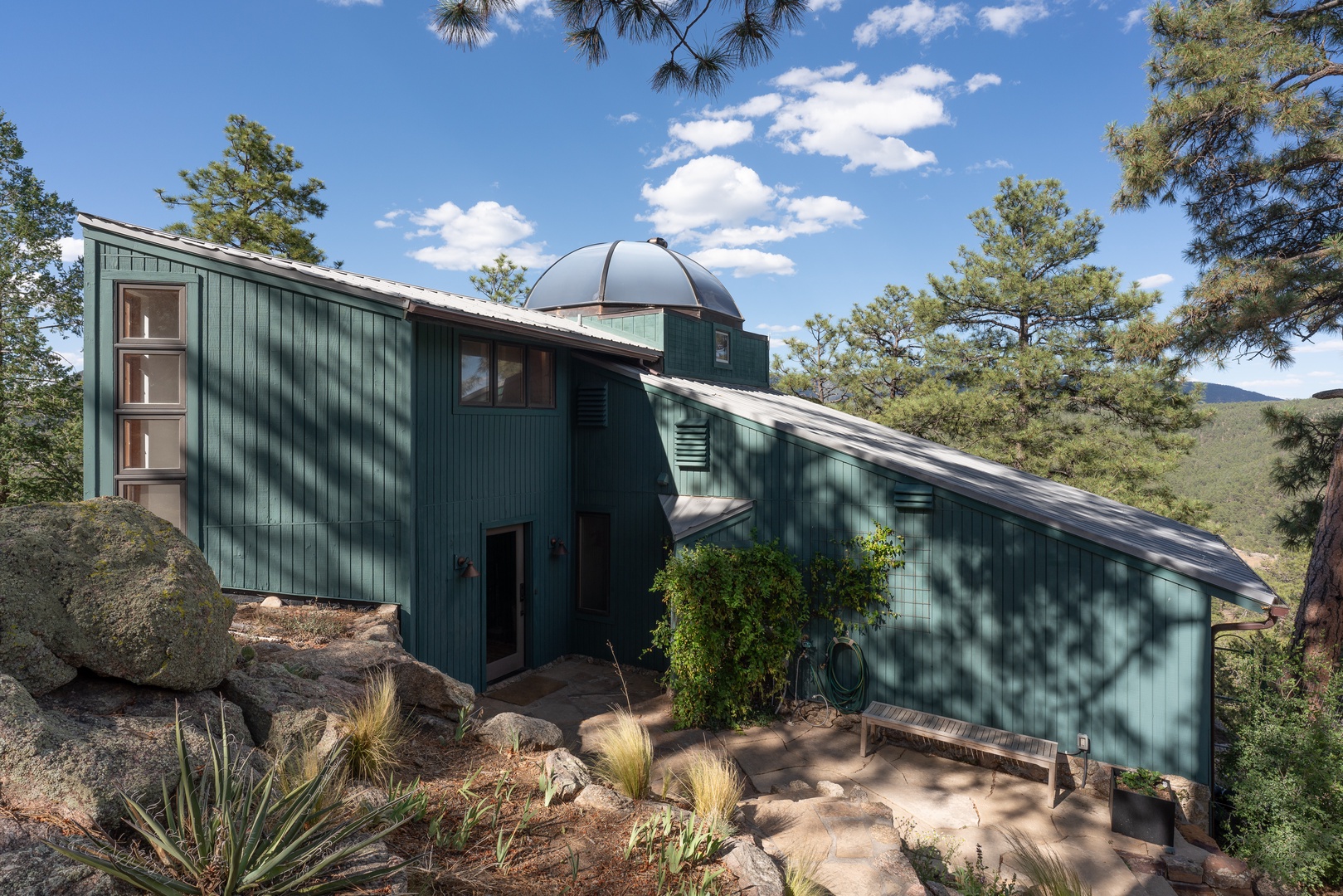 Unique mountain retreat nestled among pines with scenic views. Property features distinctive architecture blending into the natural landscape.
