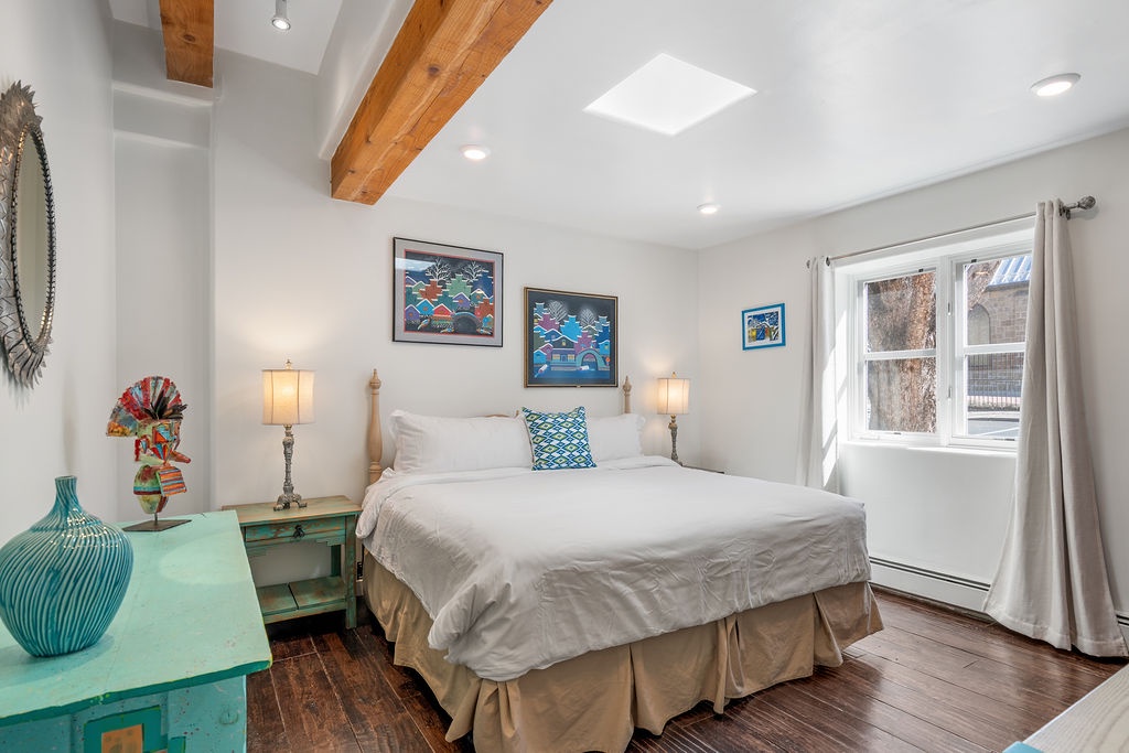 Unwind in your bright bedroom featuring exposed wood beams, colorful local artwork, and soft linens that promise restful nights.