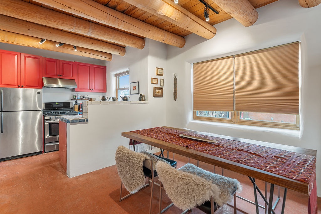 Your rustic kitchen features striking coral cabinets, exposed wooden beams, and a beautiful dining table where you'll savor home-cooked meals.