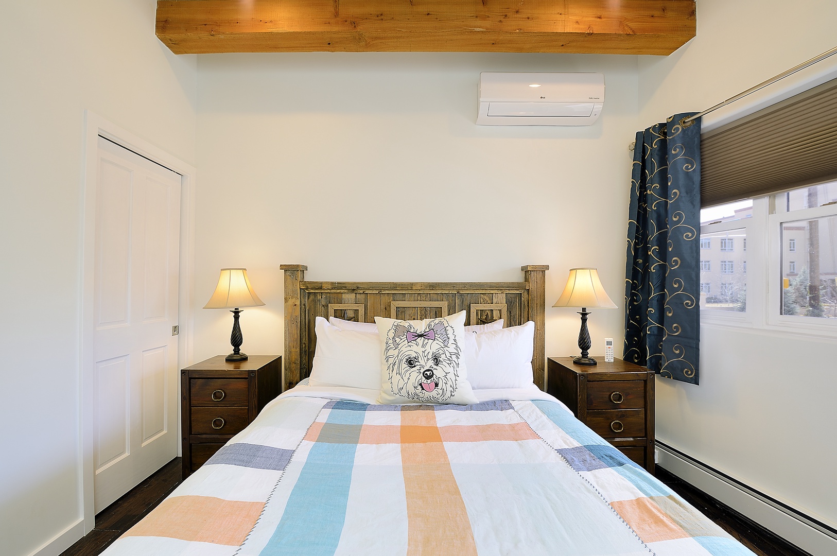 Sink into this cozy bedroom where rustic wood beams meet modern comfort, complete with adorable puppy pillow and city views.