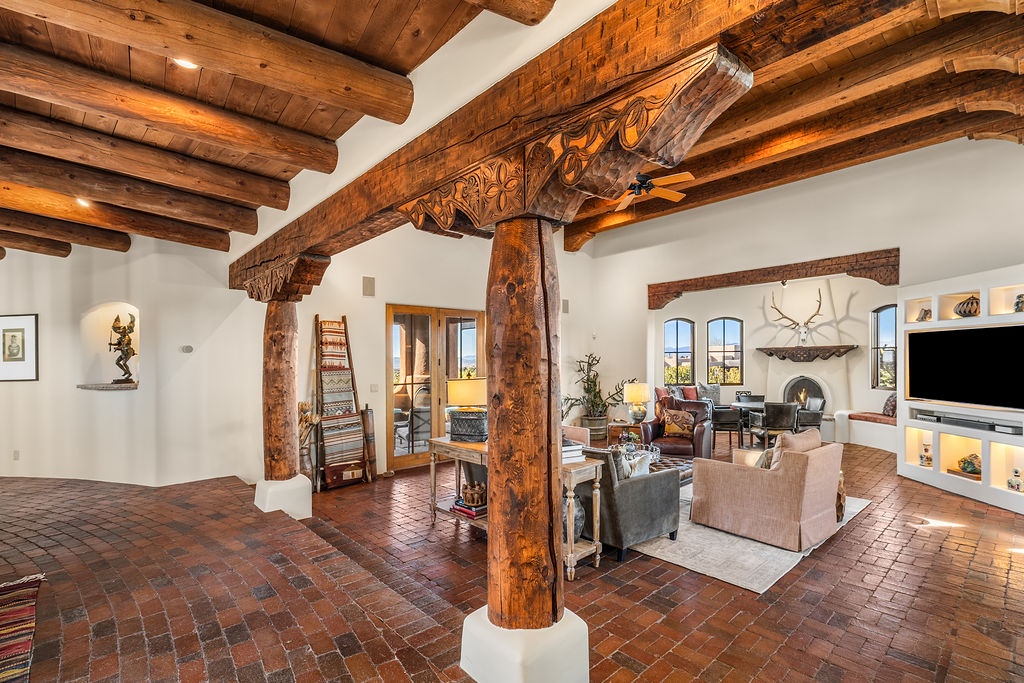 Relax in this stunning living room where handcrafted wooden beams and exposed brick create authentic southwestern charm beneath soaring ceilings.