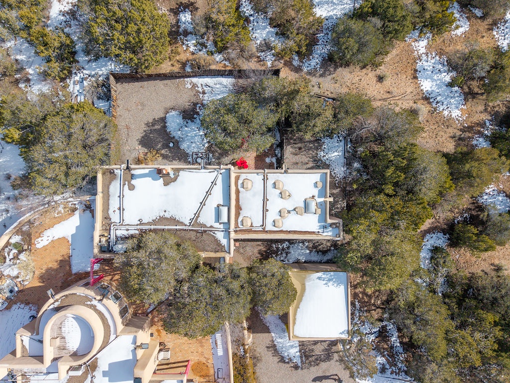 Aerial view of the property nestled among mature trees, with winter snow dusting the surrounding landscape and natural areas.
