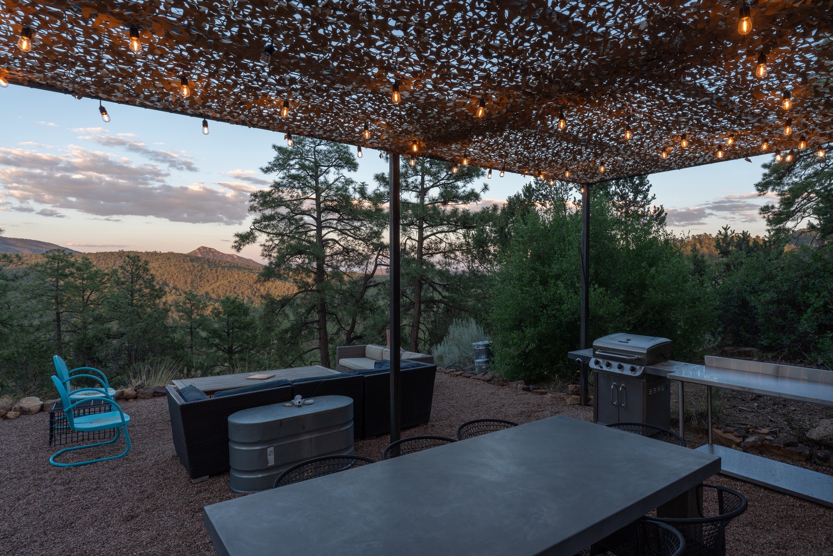 An outdoor patio with mountain views, fairy lights, a barbecue grill, and cozy seating—perfect for evening gatherings under the stars and enjoying the natural surroundings.