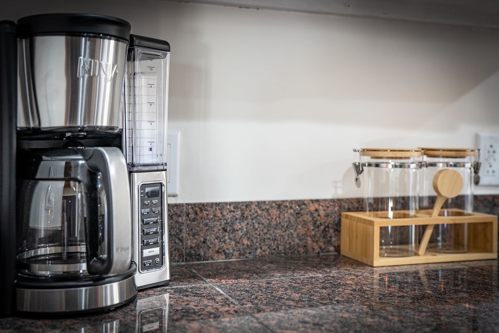 Your mornings just got brighter with this sleek coffee maker and thoughtfully arranged tea station, perfect for savoring your first sip of the day.