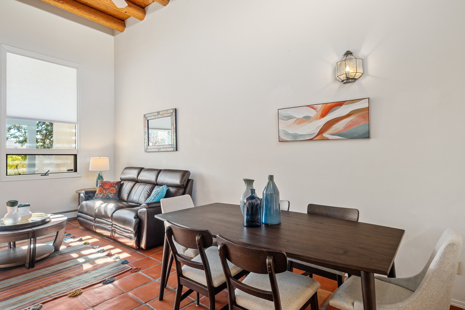 Relax in your stylish living space featuring warm wood beam ceilings, comfortable leather seating, and a welcoming dining area perfect for memorable meals together.