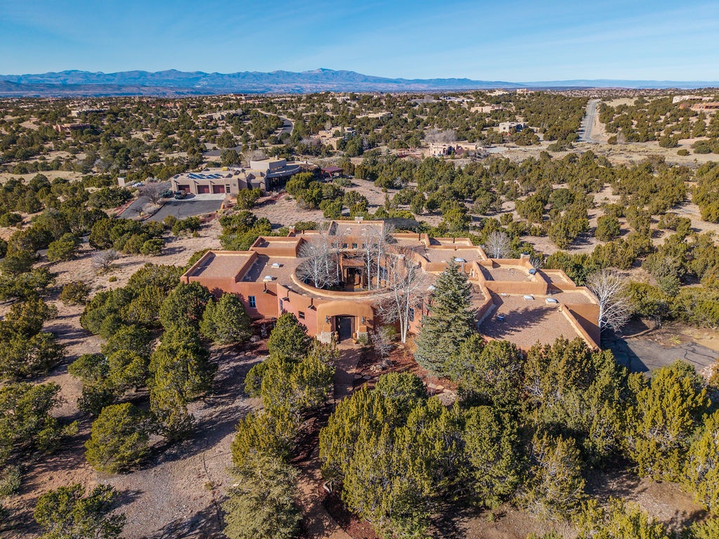 Distinctive adobe-style property nestled among juniper trees in high desert landscape with mountain views.