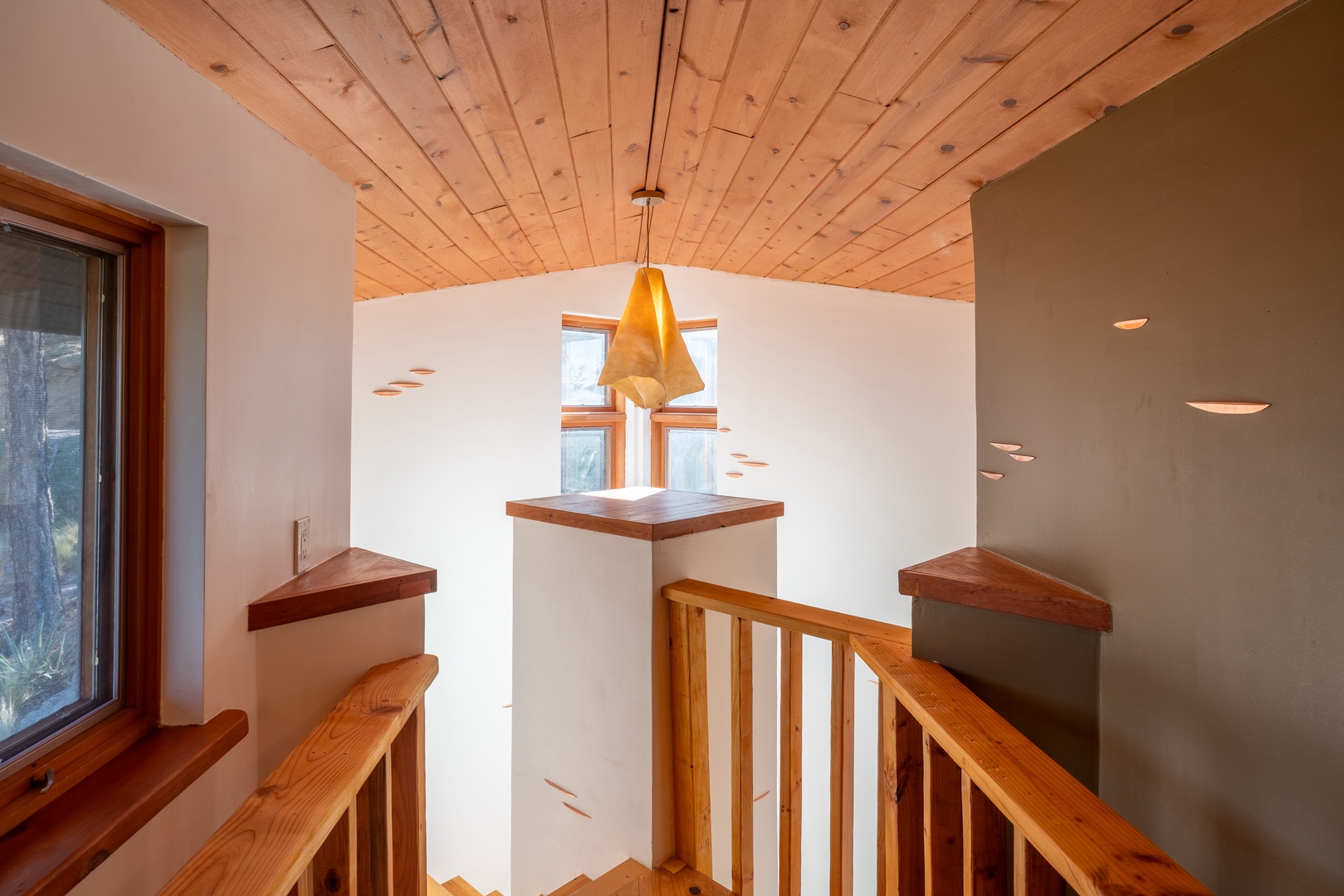 Natural light fills this airy stairwell, where warm wood railings and stunning vaulted timber ceilings create a welcoming, mountain-modern feel as you move between floors.