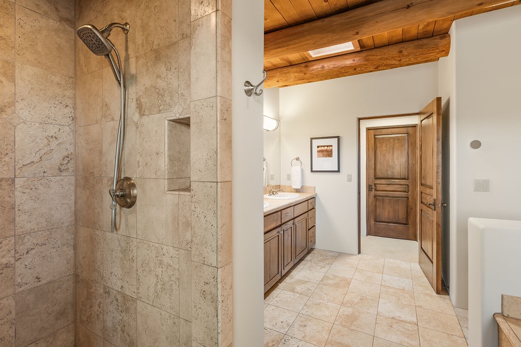 Unwind in your spa-like bathroom featuring natural stone shower, exposed wooden beams, and rustic elegance throughout.