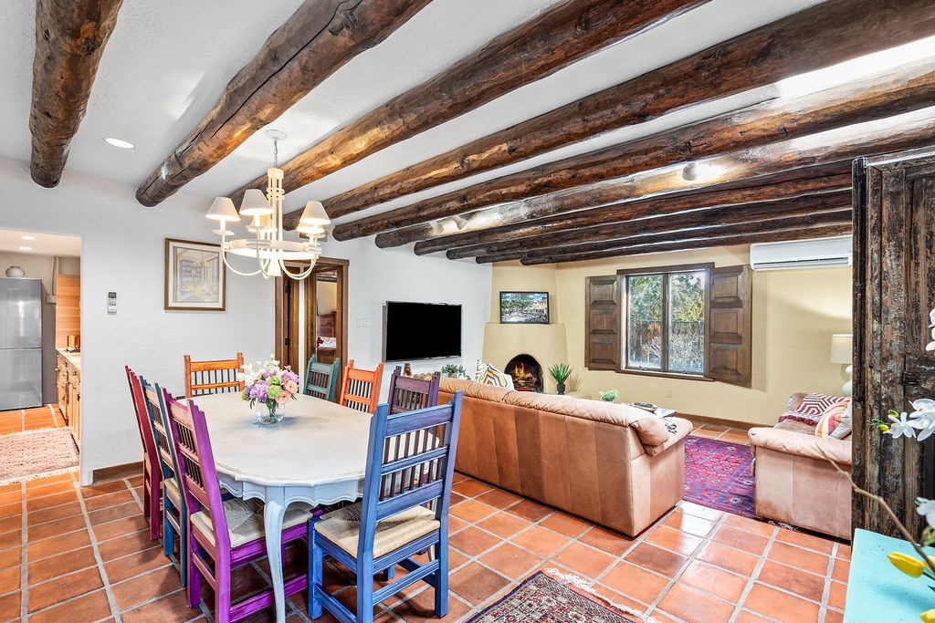 Gather around your rustic dining table beneath stunning exposed beams, then unwind by the cozy fireplace in this charming open-plan living space.