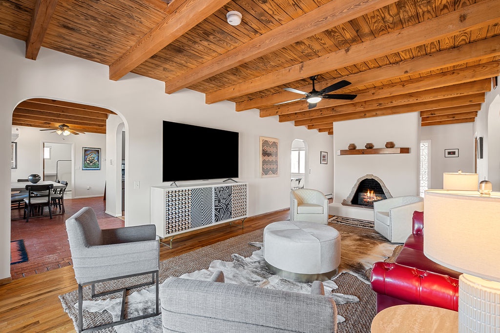 Relax in your southwestern-style living room with stunning wood beam ceilings, cozy fireplace, and modern amenities for the perfect retreat.