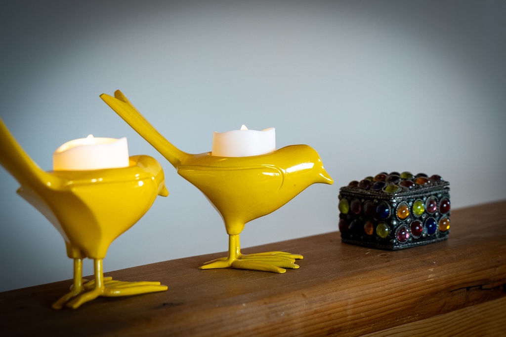 Charming yellow bird candleholders and colorful jewelry box create a whimsical touch on your bedside table.