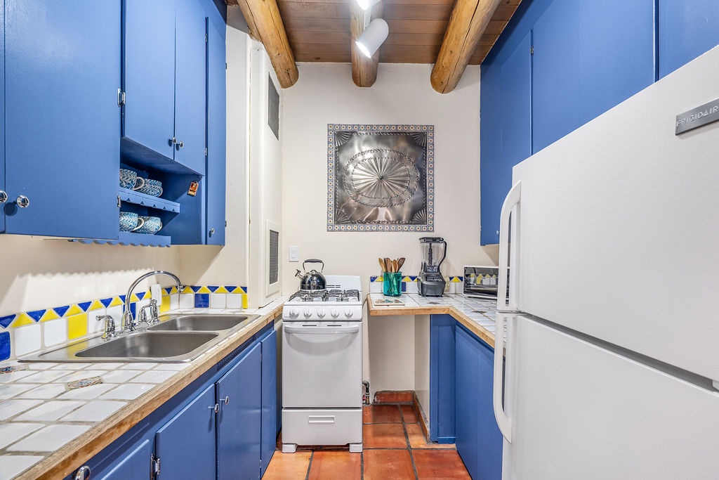 Your charming blue kitchen features colorful tile backsplash.