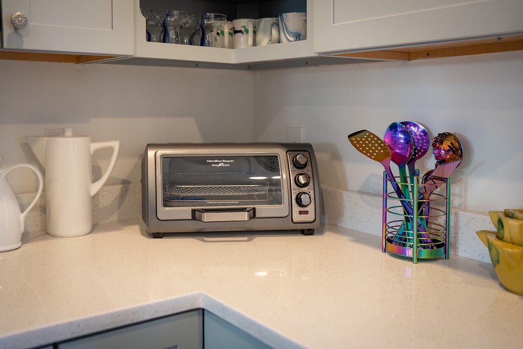 Your well-equipped kitchen corner features a convenient toaster oven and colorful serving utensils for easy meal prep.