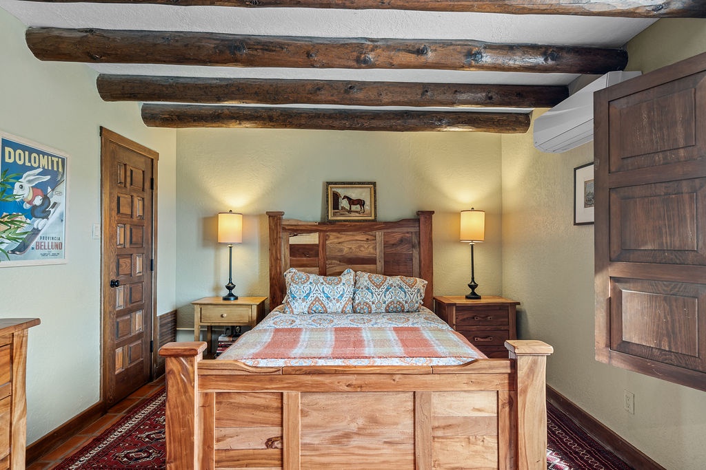 Drift off beneath rustic wooden beams in your cozy bedroom, where warm lighting and handcrafted furnishings create your perfect mountain retreat.