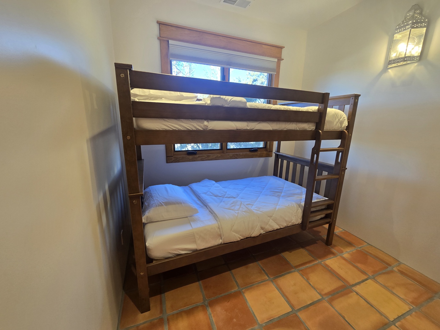 Your cozy bunk bed room offers comfortable sleeping with crisp white linens and warm tile floors beneath your feet.