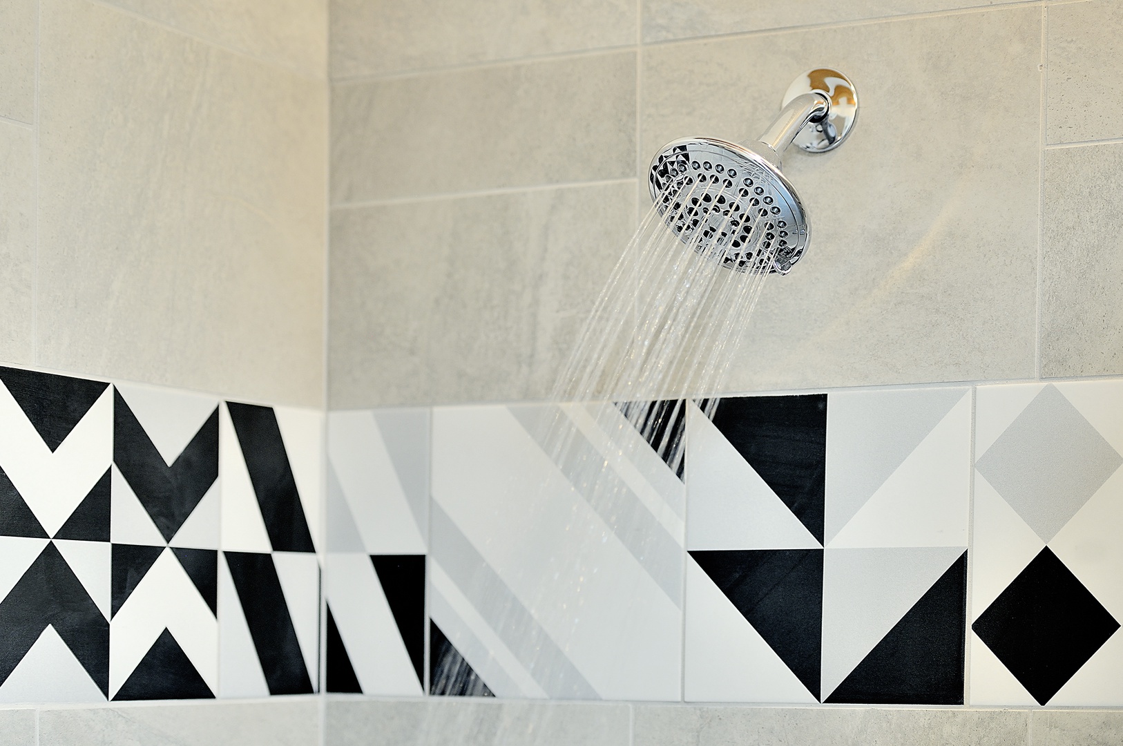 Refresh under this invigorating rainfall shower, beautifully framed by striking geometric tiles that add modern elegance to your private sanctuary.