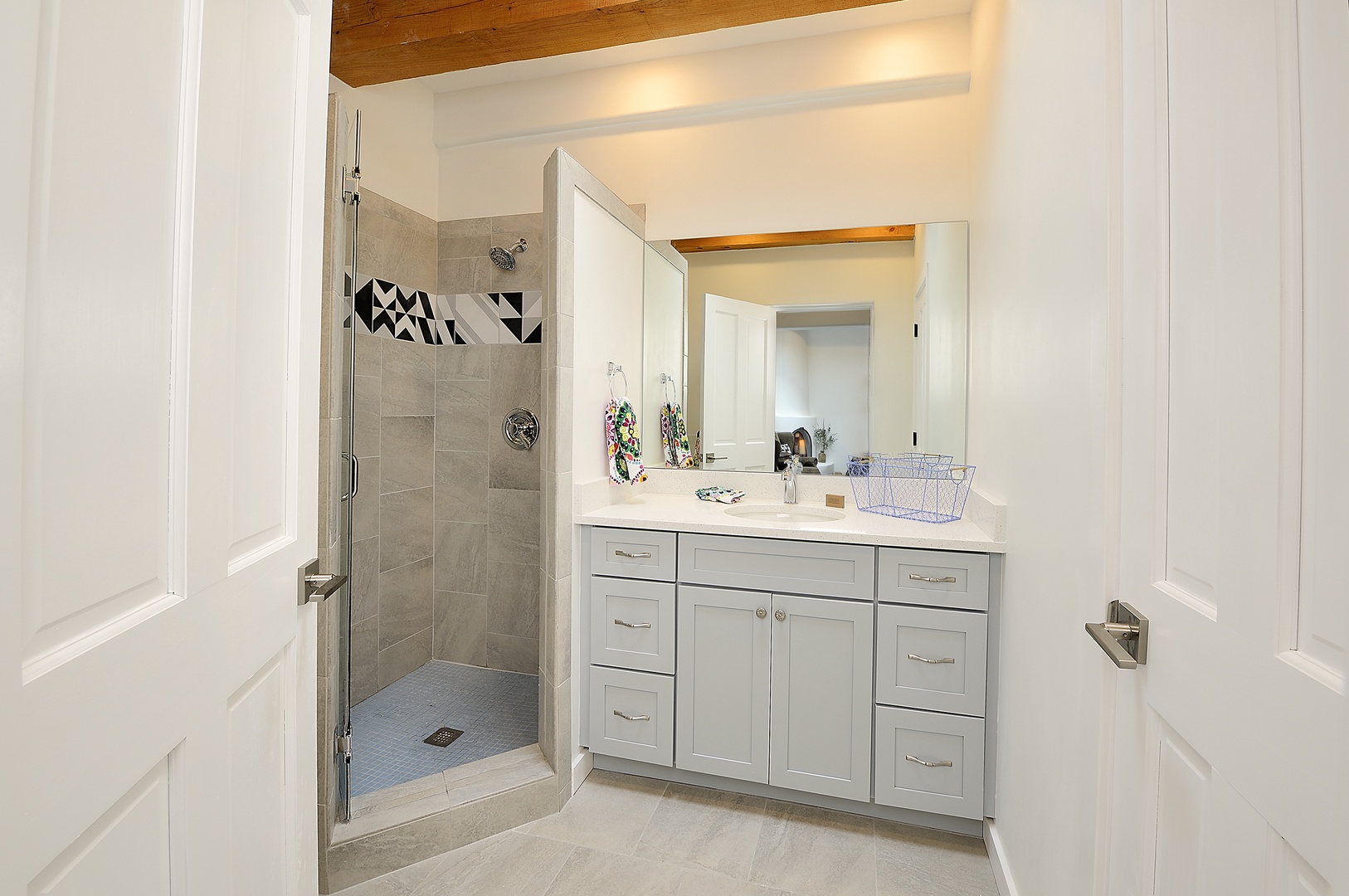 Step into your stylish bathroom with sleek gray cabinetry, geometric tile accents, and spacious glass shower.