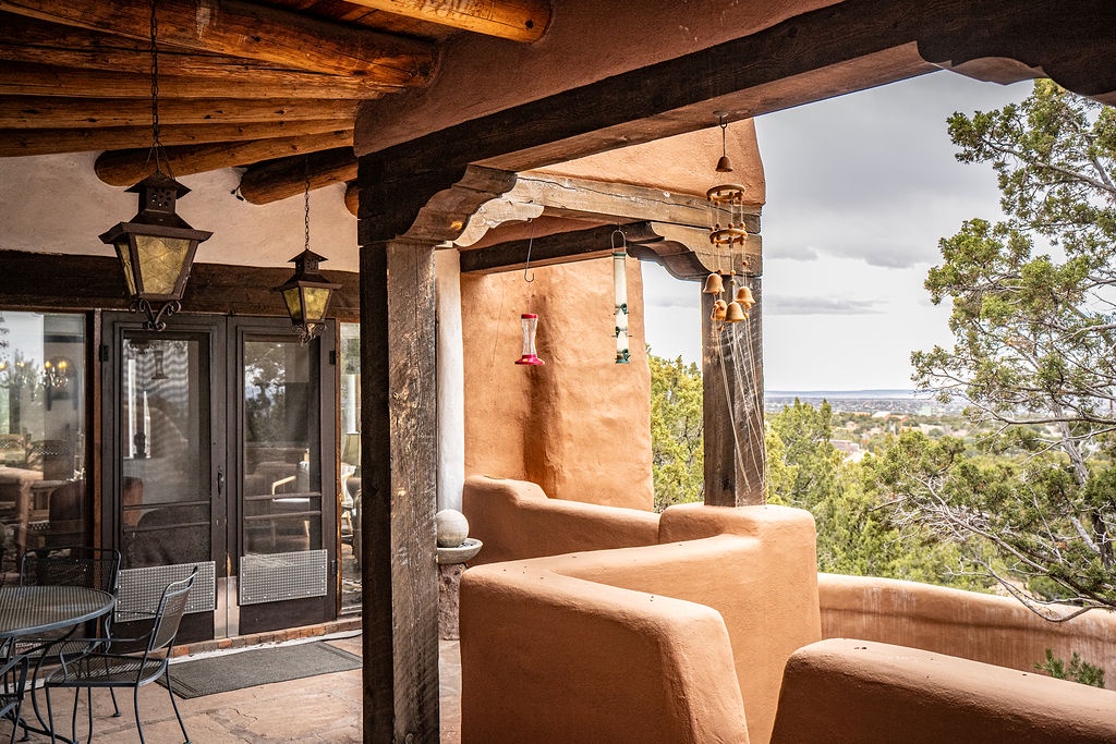 Your private outdoor shower awaits, nestled under rustic vigas with sweeping valley views stretching beyond the adobe walls.