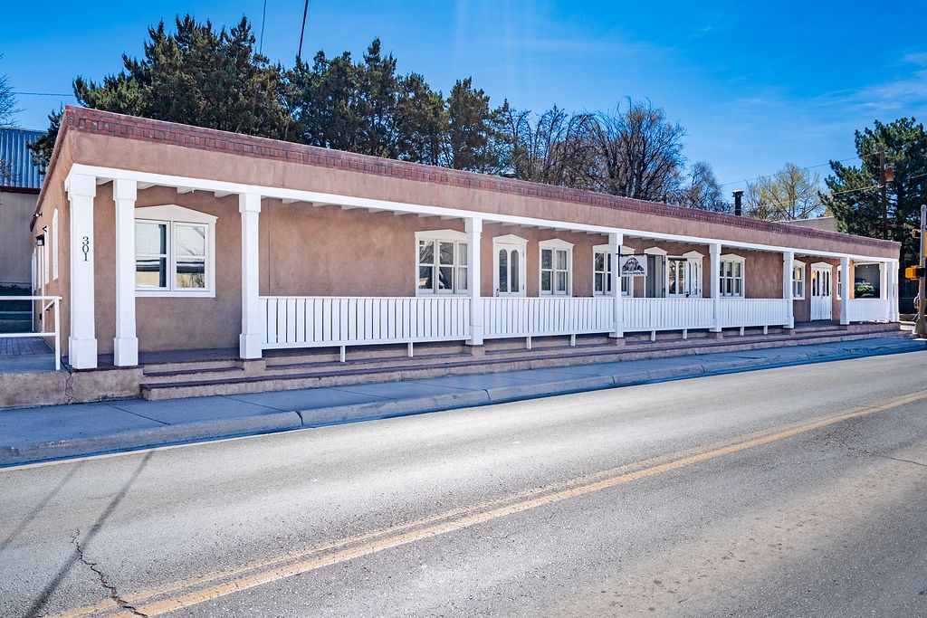 Charming single-story building featuring classic architecture with white trim and covered porch areas along a quiet street.